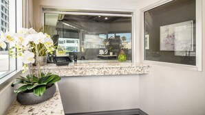 Zona de recepció amb taulell de marbre, una orquídia en test i un gran finestral amb vistes a l'exterior.