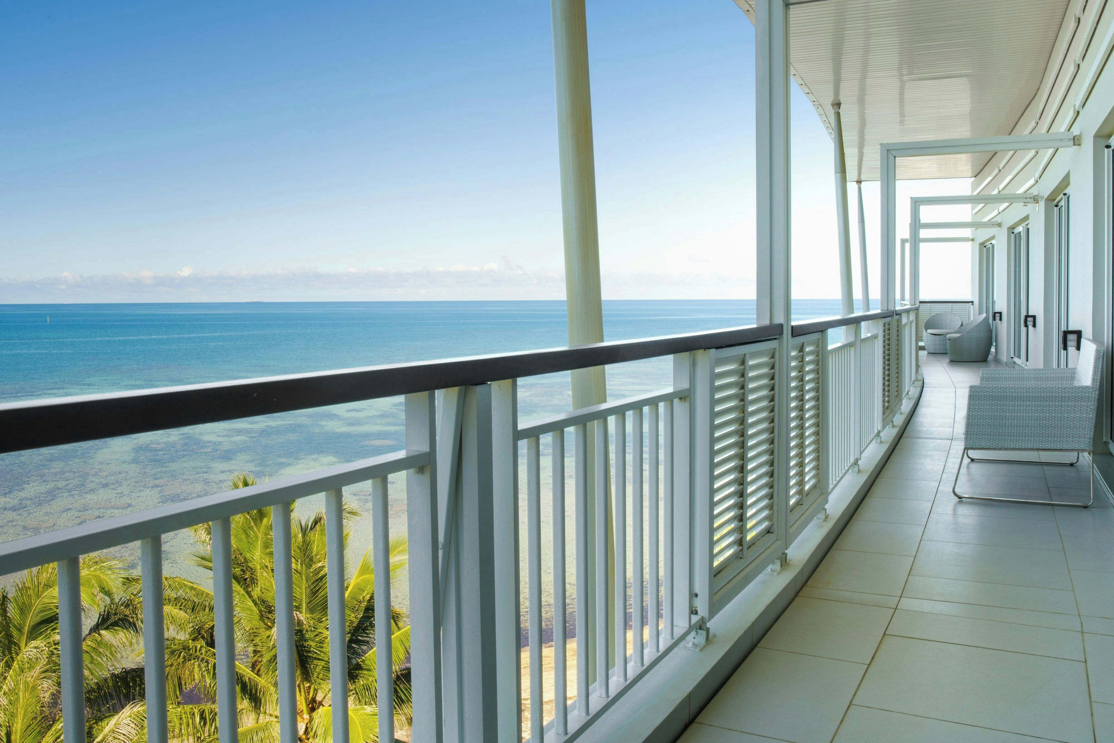 Un balcon avec vue sur l’océan et les palmiers.