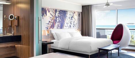 Une chambre d’hôtel moderne dotée d’un grand lit, d’une salle de bain séparée, d’un balcon avec vue et d’un ventilateur de plafond.