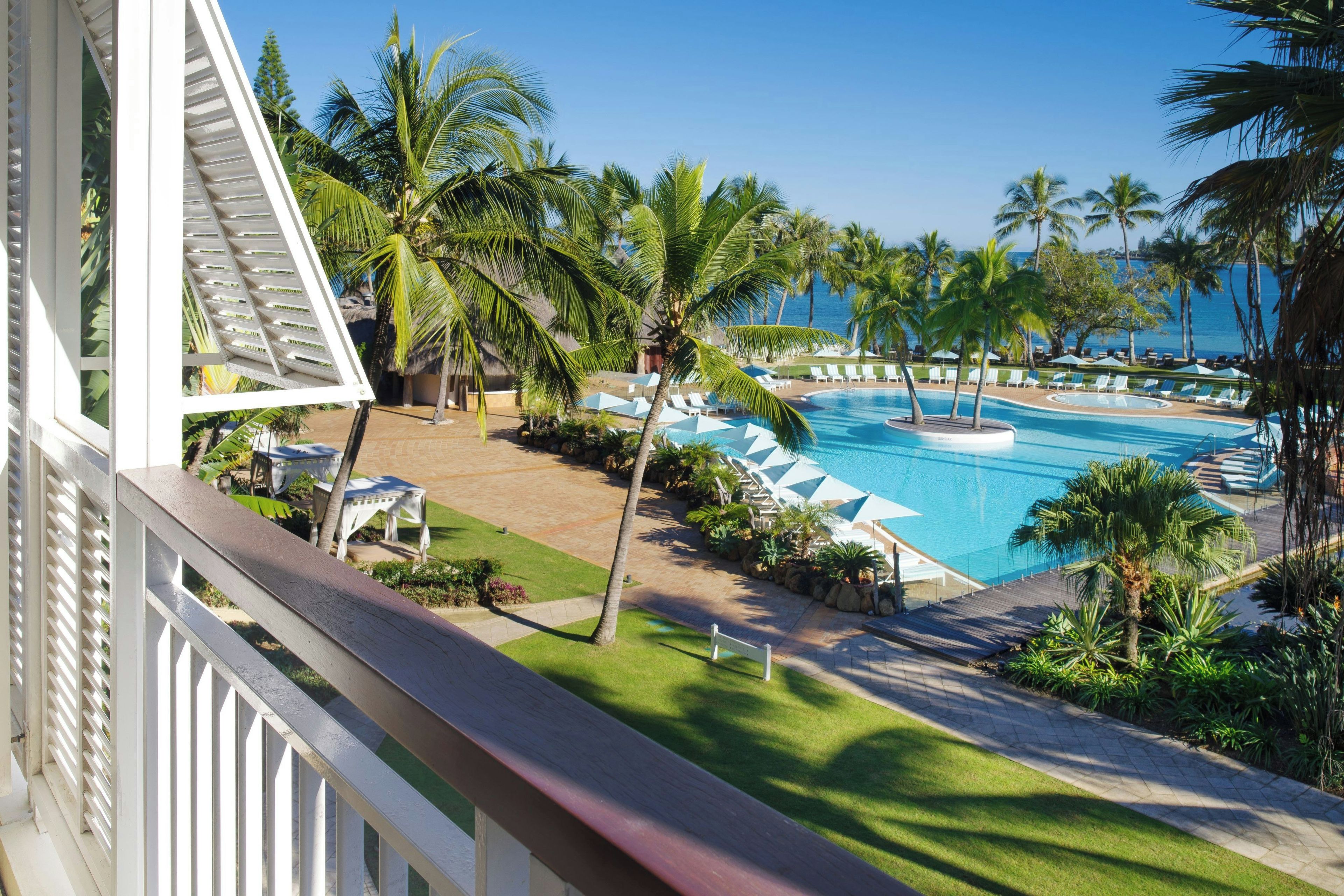A resort pool area with multiple swimming pools, palm trees, and lounge chairs.