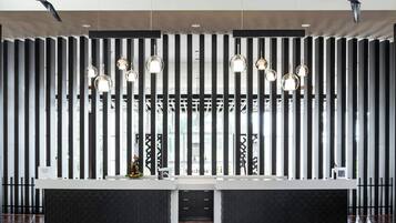 A modern reception area with a black and white striped wall, a reception desk, and pendant lighting.