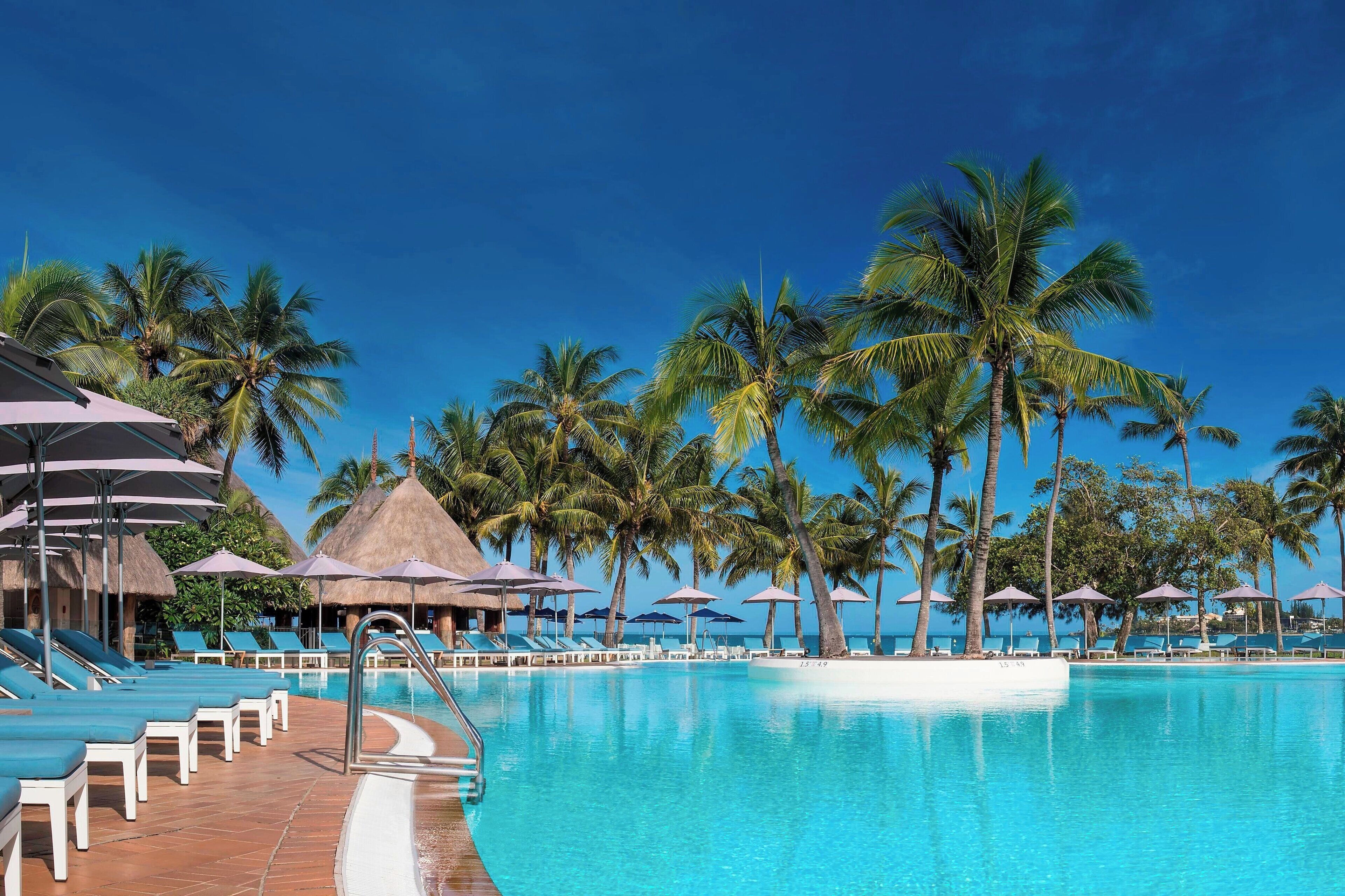 Een buitenzwembad, parasols bij het zwembad en ligstoelen