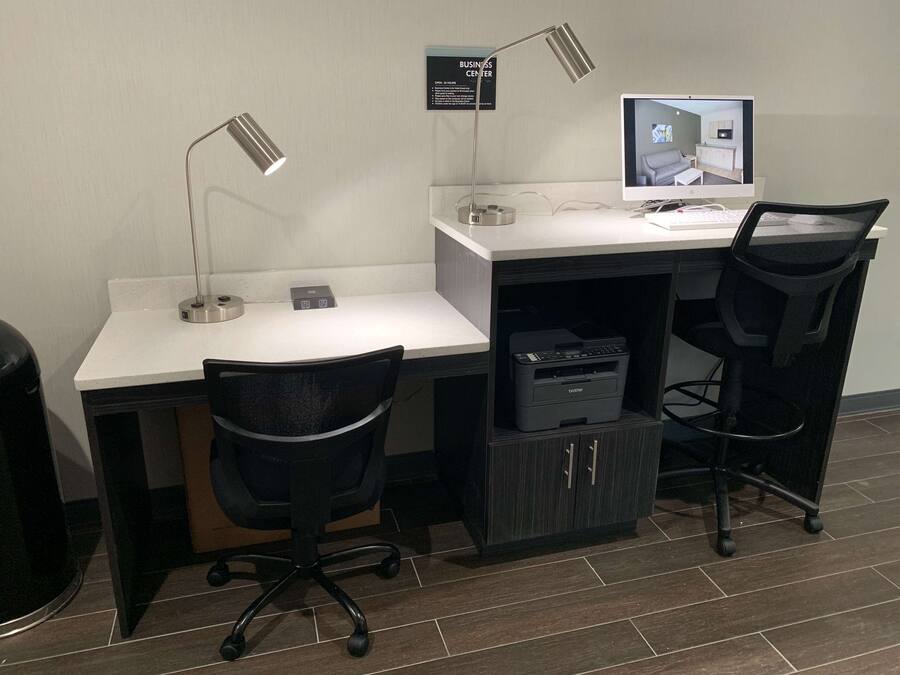 A workspace with two desks, chairs, a computer, and a printer.
