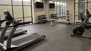Un gimnasio con cintas de correr, pesas y equipamiento de ejercicio.