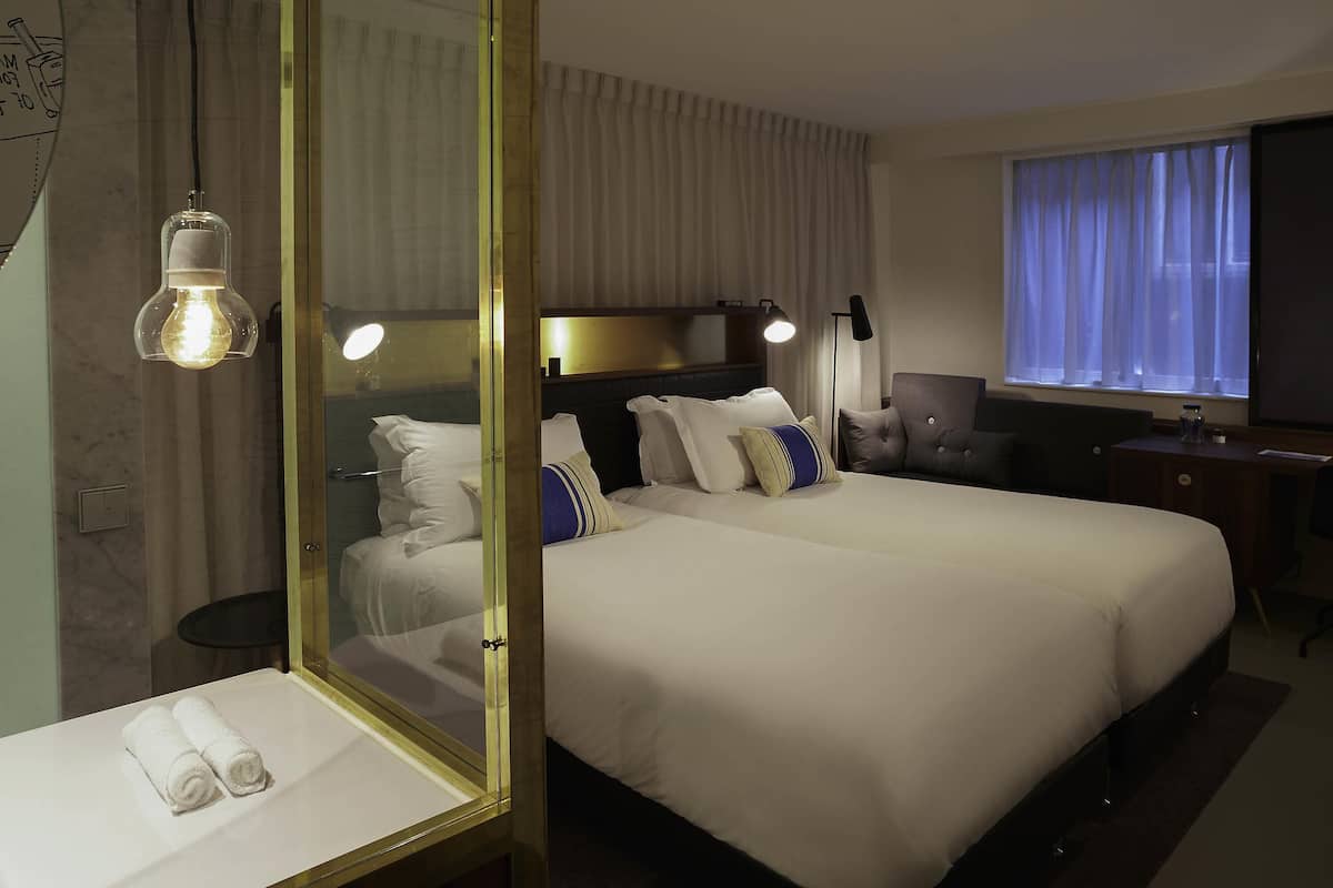 Ein Hotelzimmer mit einem großen Bett, Nachttischen, einem Schreibtisch und einem Fernseher.