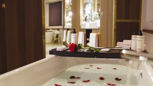 Et badekar med rosenblade, en rose og toiletartikler på et bakkesæt.