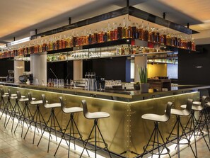 A bar area with stools, a counter with bottles, and a bookshelf labeled 'LIBRARY'. - INK Hotel Amsterdam - MGallery (Amsterdam)