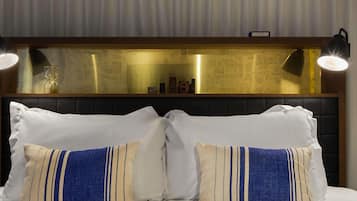 Habitación de hotel con una cama, dos almohadas decorativas, un cabecero con un reloj y una pared con diseño de mapa.