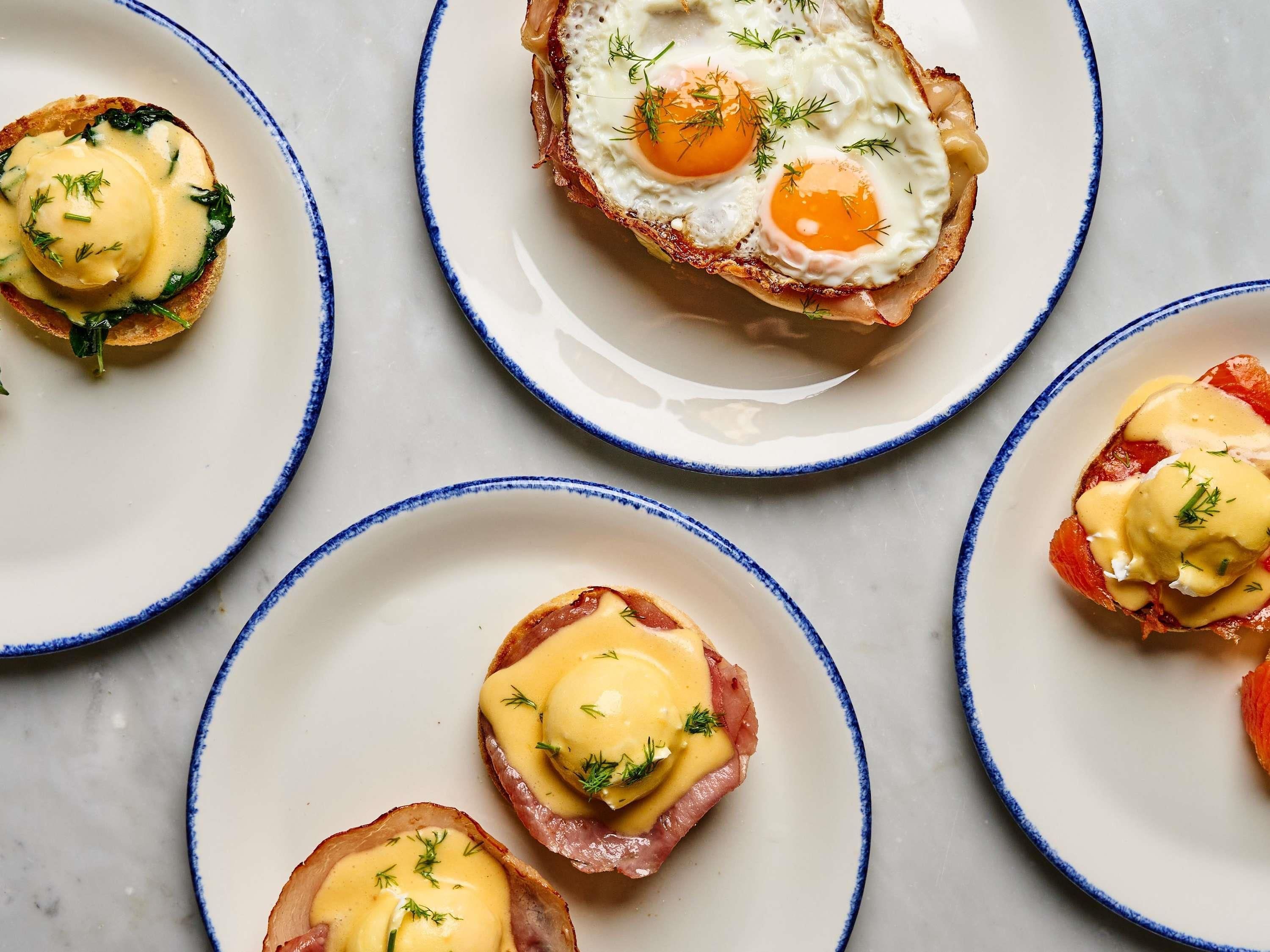 A table with plates of food, each with a piece of toast topped with eggs and a sauce.