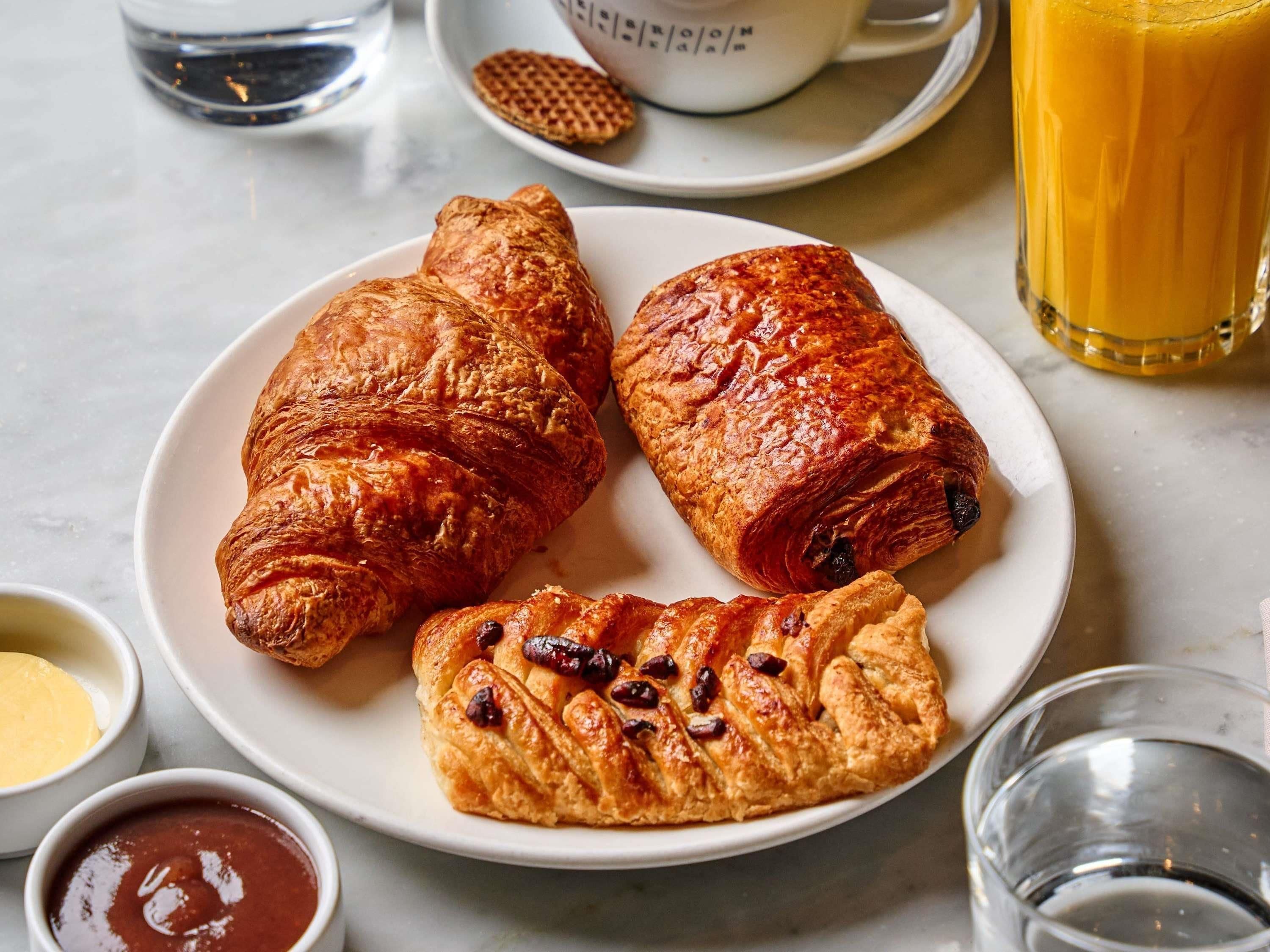 En tallrik med tre croissanter och två små skålar med tillbehör.