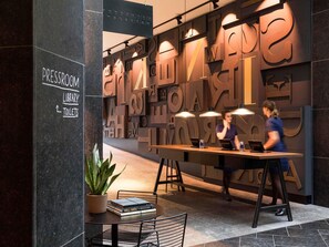 A reception desk with a sign indicating a pressroom, library, and toilets.