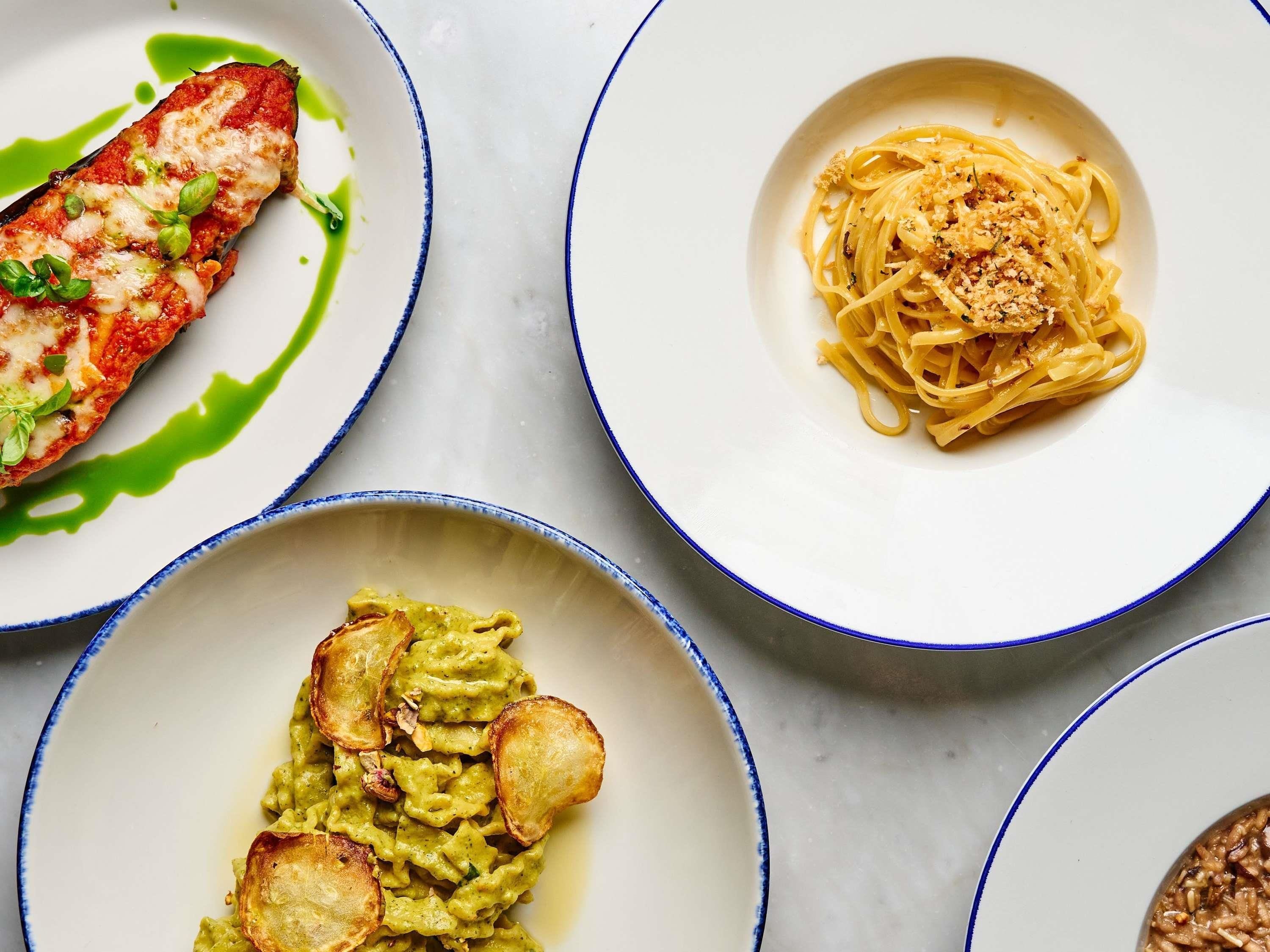 Tres platos de comida: un filete de pescado con salsa, espagueti con queso rallado y pasta verde con acompañamientos fritos.