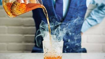A person pouring a liquid into a glass, creating smoke.