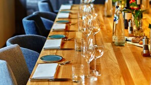 A long wooden table set for dining with chairs, wine glasses, and bottles. - INK Hotel Amsterdam - MGallery (Amsterdam)