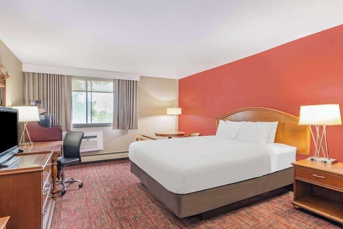 A hotel room with a bed, desk, chair, and a television.