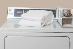 A GE commercial dryer with a folded white towel on top. - Ramada by Wyndham Grand Forks (Grand Forks)