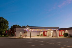 A hotel with a covered entrance, a fountain, and a parking lot. - Ramada by Wyndham Grand Forks (Grand Forks)