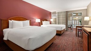 A hotel room with two beds, a desk, and a view of the outside. - Ramada by Wyndham Grand Forks (Grand Forks)