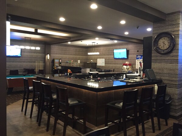 A bar area with a pool table, multiple TVs, and a clock on the wall. - Ramada by Wyndham Grand Forks (Grand Forks)