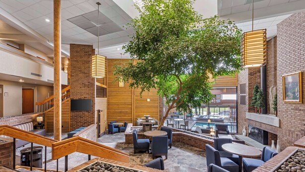A spacious indoor area with a central tree, multiple seating arrangements, and a staircase. - Best Western Plus Landmark Inn (Park City)