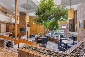 A spacious indoor area with a central tree, multiple seating arrangements, and a staircase. - Best Western Plus Landmark Inn (Park City)