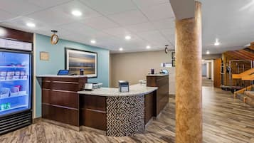 A reception area with a counter, a digital screen, and a refrigerator.