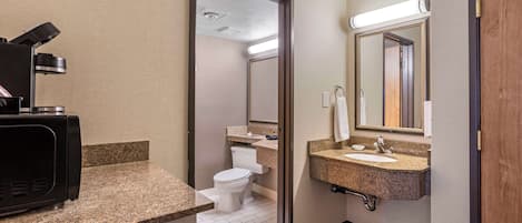 Un baño de hotel pequeño con lavamanos, espejo y retrete.