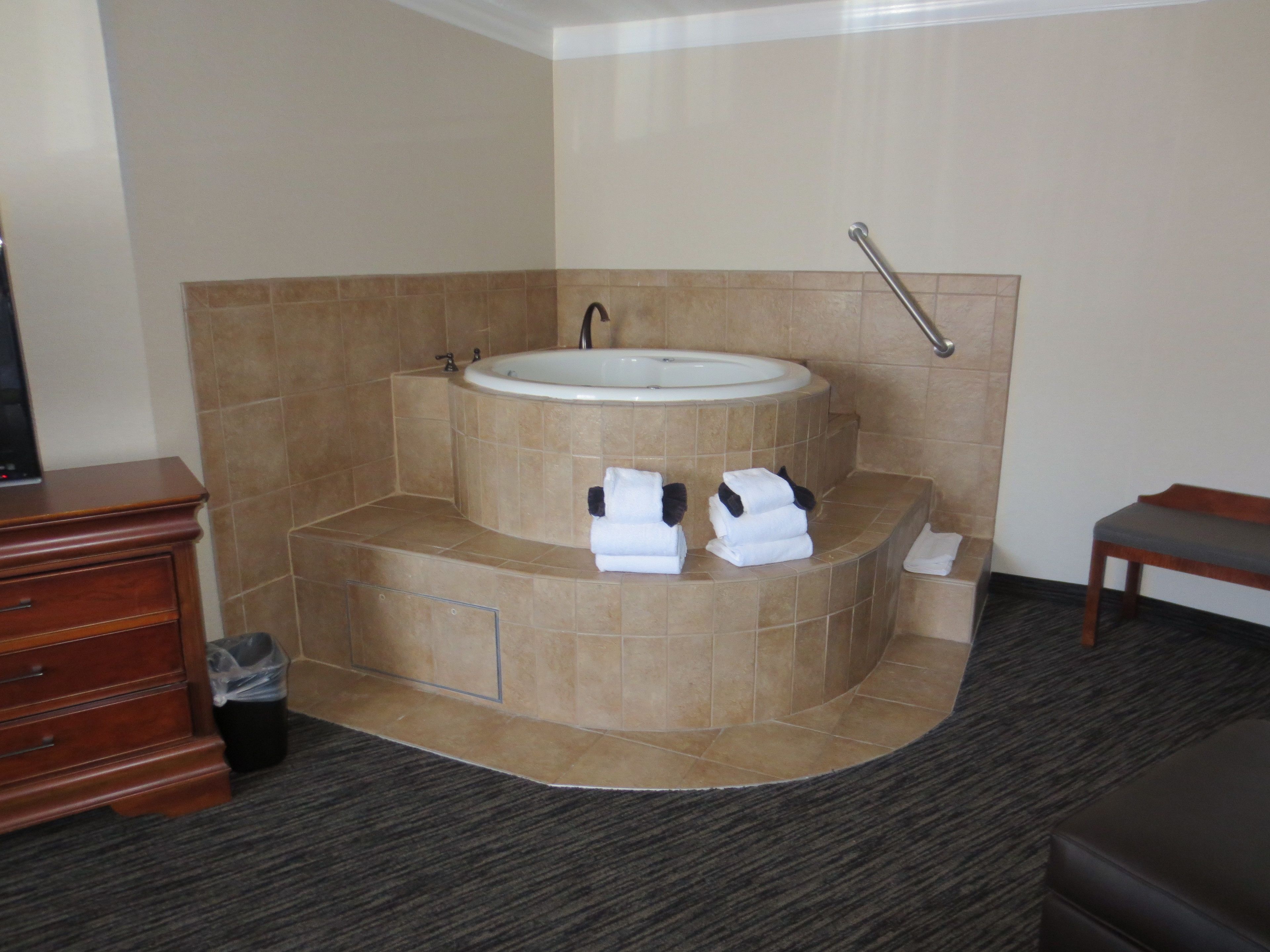 A bathroom with a freestanding bathtub, a wooden vanity, and a trash bin.