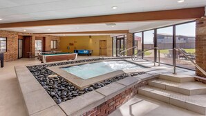 A pool area with a hot tub, a pool table, and a staircase leading to an outdoor patio. - Best Western Plus Landmark Inn (Park City)