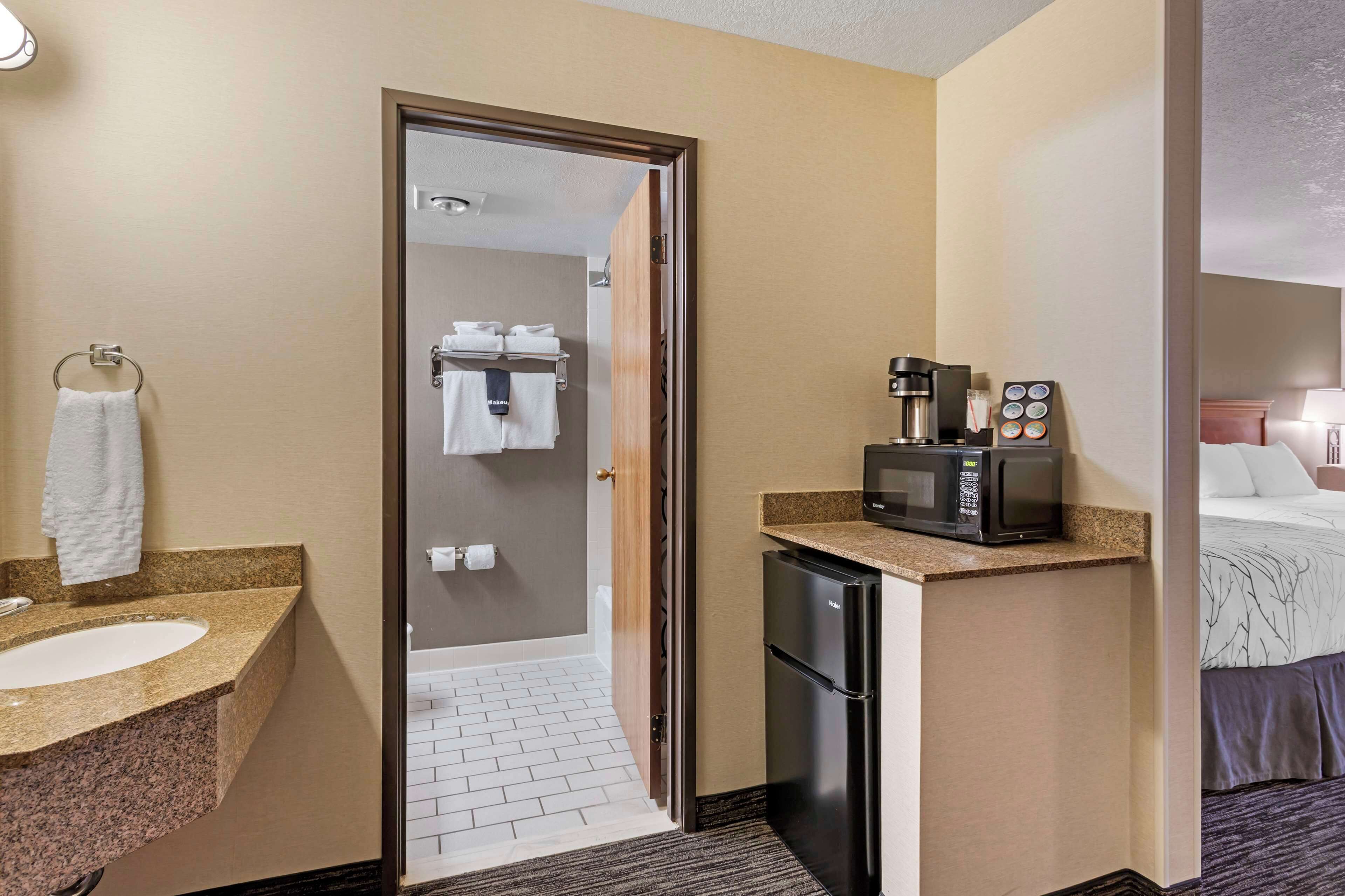 A hotel bathroom with a sink, towel rack, and a shower area visible through a glass door.