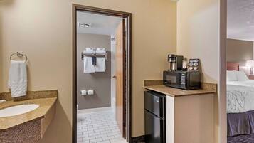 A hotel bathroom with a sink, towel rack, and a shower area visible through a glass door.