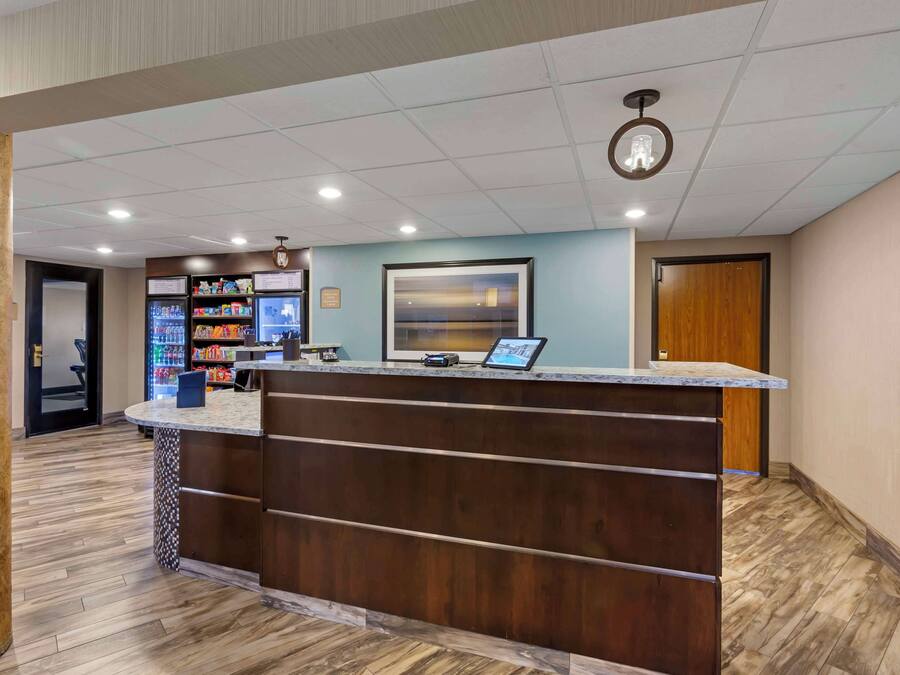 A reception area with a wooden counter, a refrigerator stocked with beverages, and a framed picture on the wall.