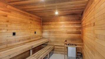 A sauna room with wooden benches and a small table with towels.