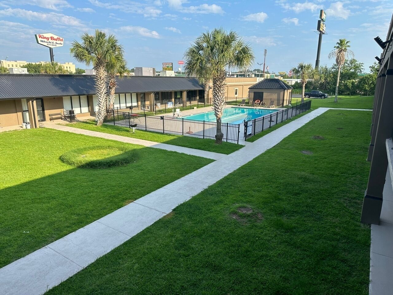 Un hôtel doté d’une piscine, d’un espace clos et d’une pelouse bien entretenue.