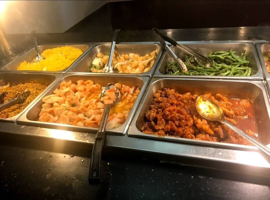 A buffet with various food options including shrimp, noodles, and vegetables.