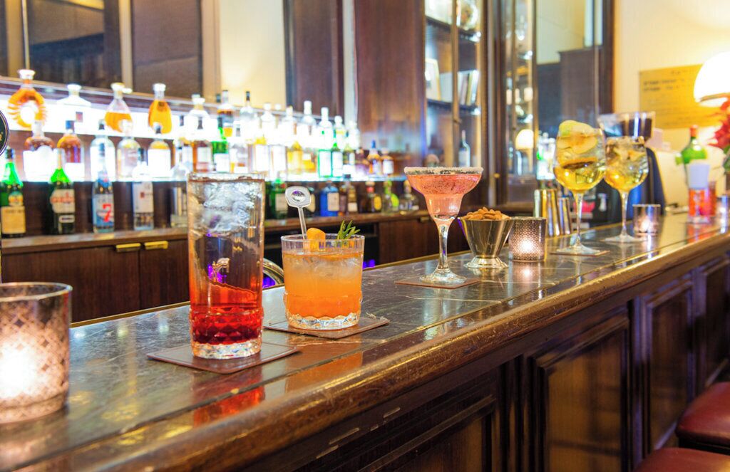 Un bar con varias botellas y vasos de bebidas.