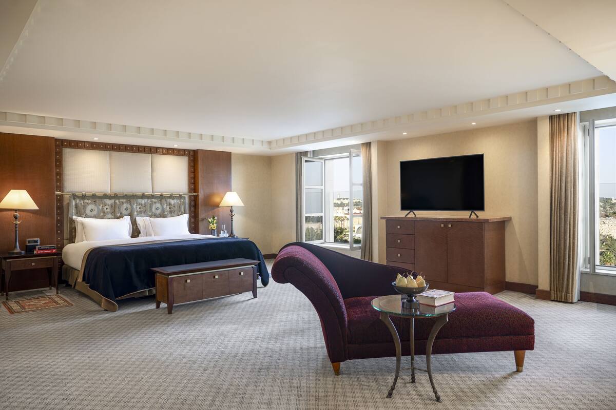 A hotel room with a bed, a desk, a TV, a chair, and a window.