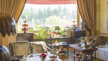 A dining area with a table set for a meal, chairs, a buffet cart, and a view of the outdoors.