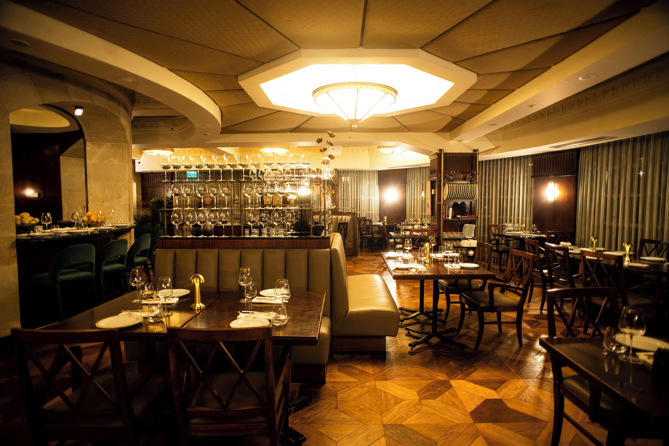 A restaurant with a bar area, wooden tables, and a patterned floor.