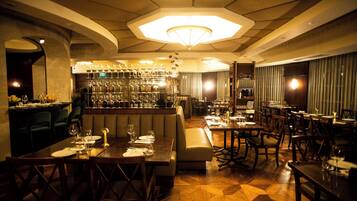 A restaurant with a bar area, wooden tables, and a patterned floor.