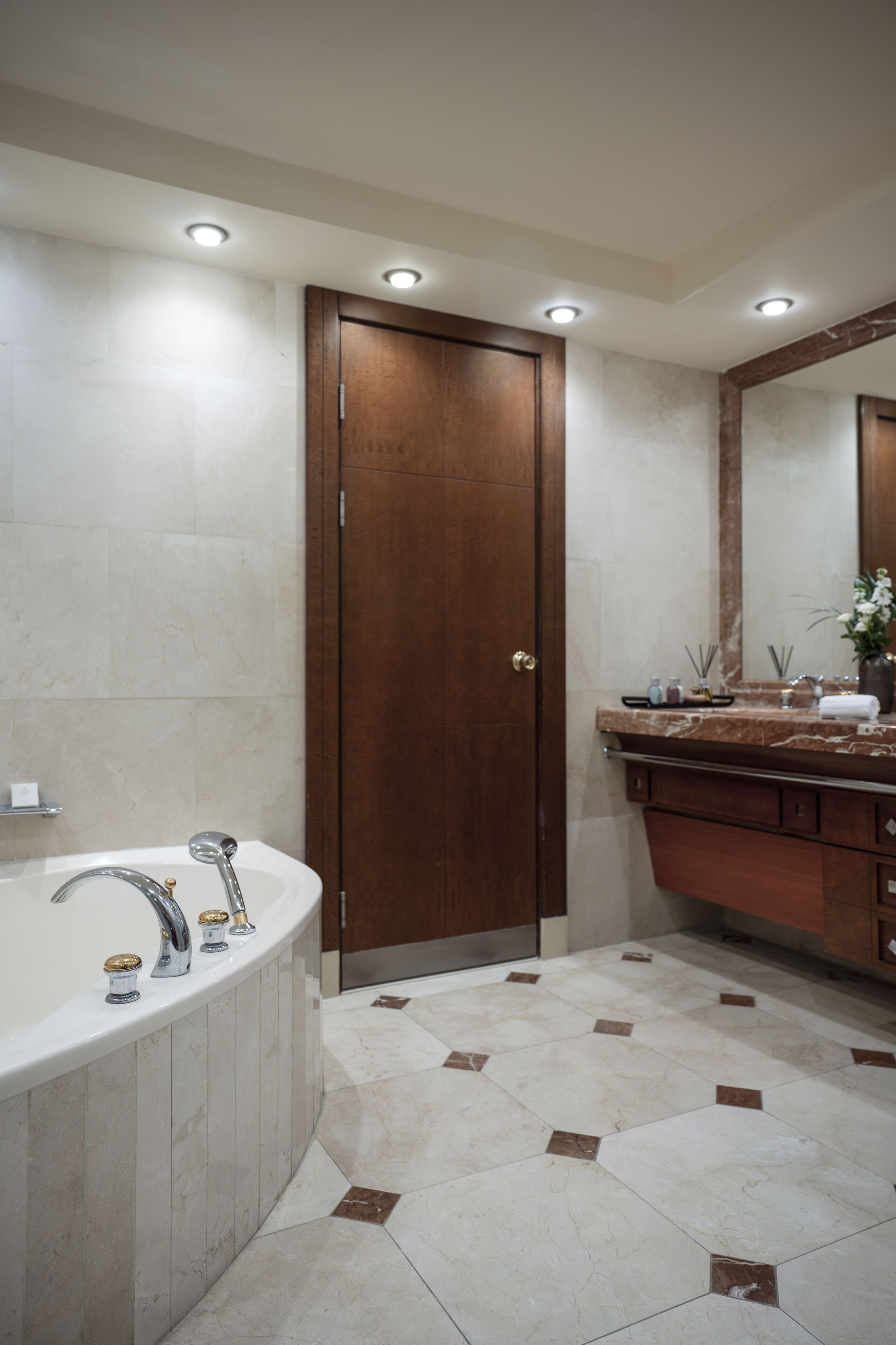 Ein Badezimmer mit einer großen Badewanne, einer Holztür und einem Marmorboden.