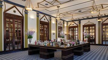 A large, ornate bar area with a long counter, multiple hanging light fixtures, and a patterned floor.
