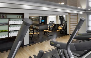 A gym with exercise equipment, towels, and a television.