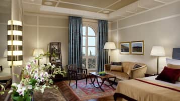 Una habitación de hotel con un ventanal grande, un sofá, una mesa de comedor y una estantería.