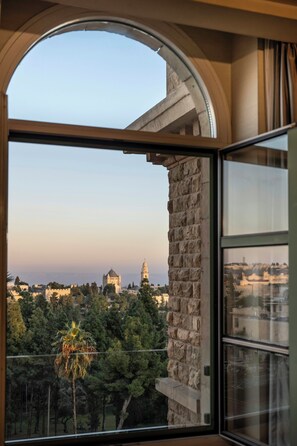 A room with a large arched window overlooking a cityscape with historic buildings and a clear sky.