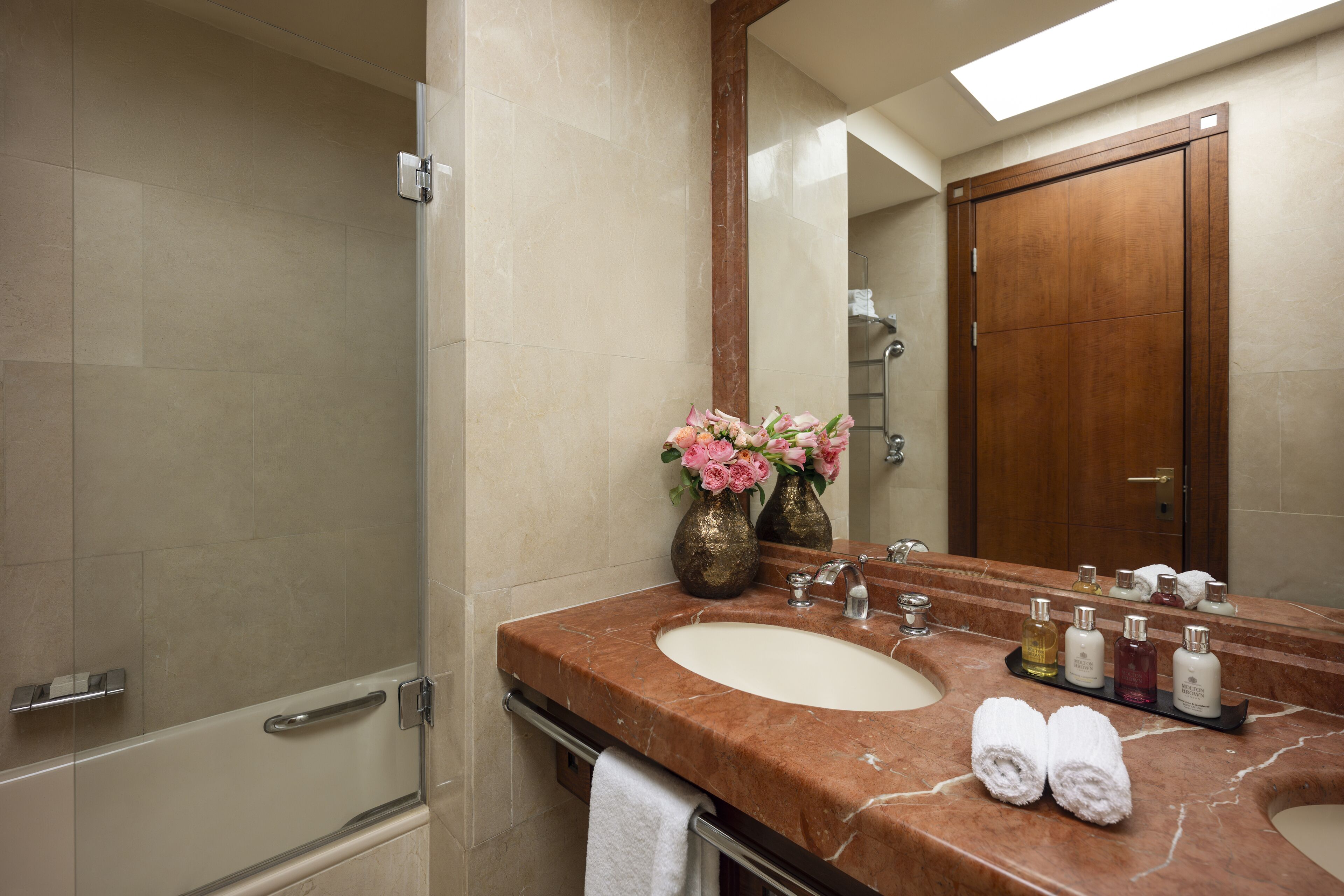 A bathroom with a marble sink, a large mirror, and a shower.