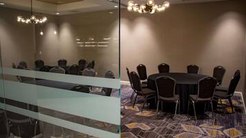 A conference room with a round table and chairs, a patterned carpet, and a modern chandelier.