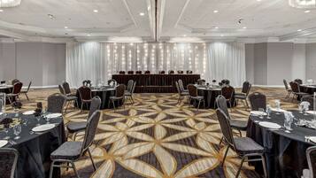 Un salón de conferencias con mesas redondas, sillas y un escenario.
