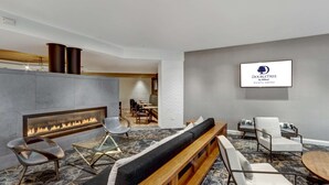 Un área de estar moderna con chimenea, asientos y un televisor que muestra el logotipo de DoubleTree by Hilton.
