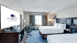 Habitación de DoubleTree by Hilton con dos camas, un escritorio, un televisor y un ventanal grande con cortinas.